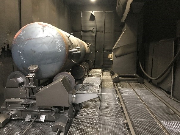 A glance into the combined blast room and turbine blasting plant. On the right the turbine carriage, on the left the workpiece (gas tank).